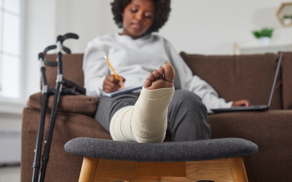 A young woman in a cast filling out paperwork from her injury attorney